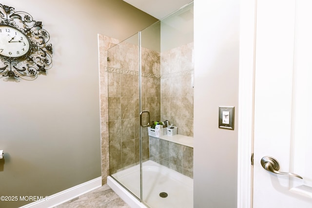 bathroom featuring tile patterned flooring, baseboards, and a stall shower