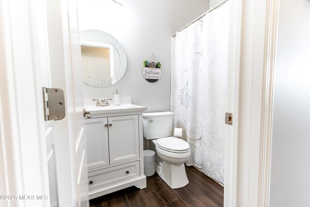 bathroom featuring a shower with shower curtain, toilet, wood finished floors, and vanity