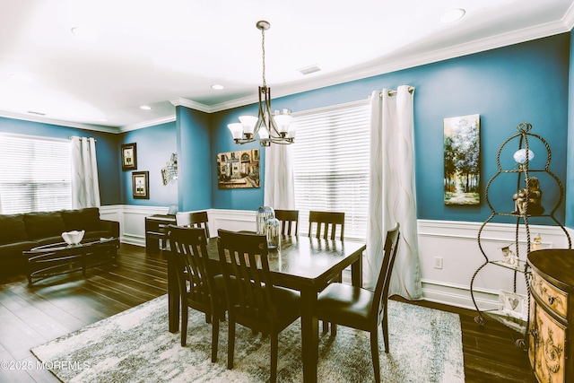 dining room featuring visible vents, wood finished floors, wainscoting, crown molding, and a chandelier