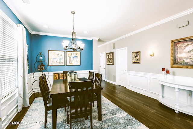 dining area featuring a wainscoted wall, a notable chandelier, dark wood-style floors, crown molding, and a decorative wall