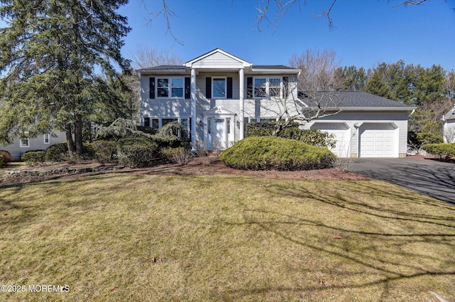 greek revival inspired property featuring a front yard, an attached garage, and driveway