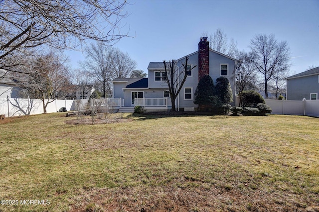 rear view of property with a wooden deck, a yard, fence, and a chimney