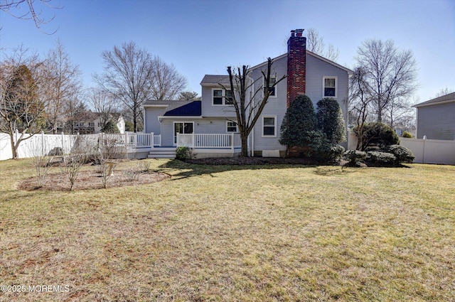 back of house with a lawn, a deck, a chimney, and fence