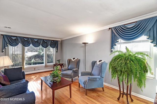 living room featuring baseboard heating, crown molding, baseboards, and wood-type flooring