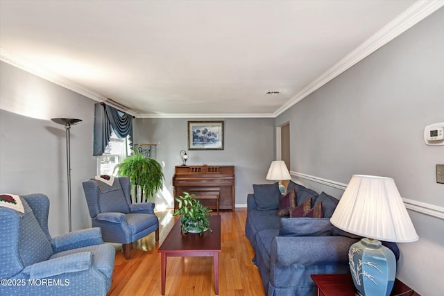 living room with visible vents, crown molding, baseboards, and wood finished floors