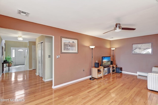 living area featuring visible vents, baseboards, light wood-type flooring, a ceiling fan, and a baseboard radiator