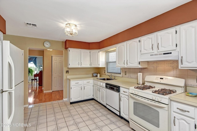 kitchen featuring white appliances, white cabinets, under cabinet range hood, and a sink