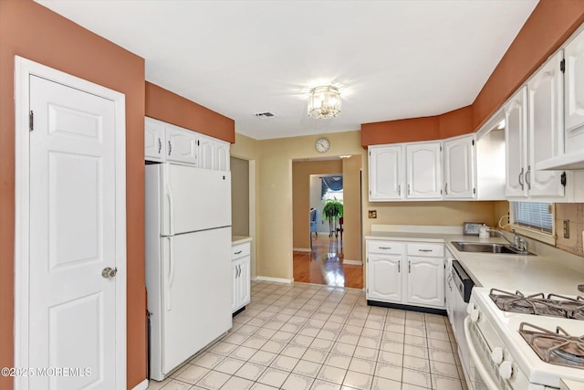 kitchen with visible vents, light countertops, white cabinets, white appliances, and a sink