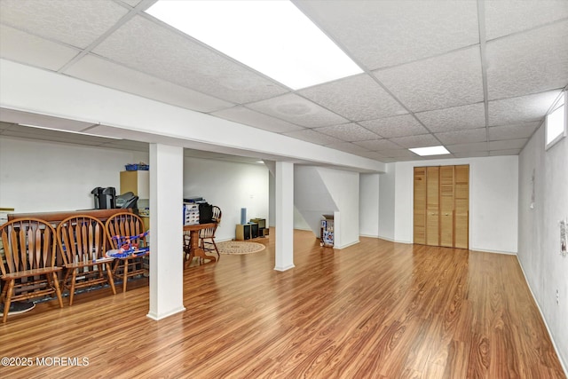 finished basement with a paneled ceiling and wood finished floors