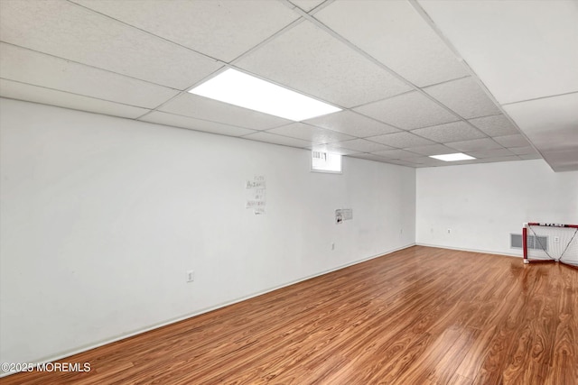 below grade area featuring wood finished floors, visible vents, and a drop ceiling