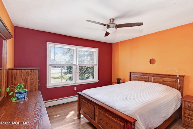 bedroom featuring ceiling fan, a baseboard radiator, and wood finished floors