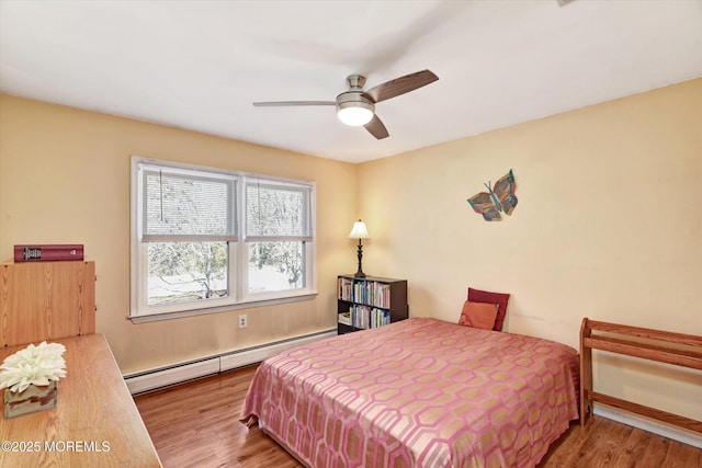 bedroom featuring wood finished floors, baseboard heating, and ceiling fan