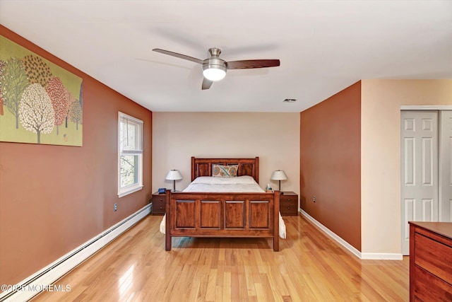 bedroom with light wood finished floors, visible vents, a baseboard heating unit, ceiling fan, and baseboards