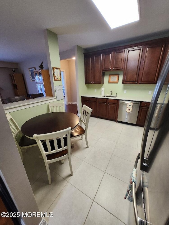 kitchen featuring light tile patterned floors, dishwasher, light countertops, and a sink