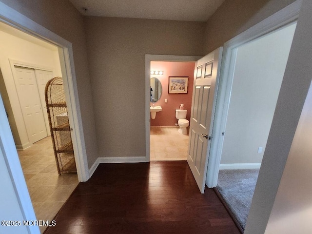 hall with baseboards and wood finished floors