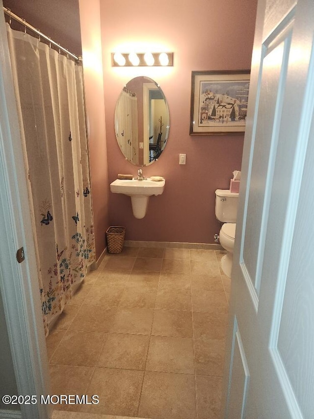 bathroom featuring a sink, baseboards, toilet, and tile patterned floors