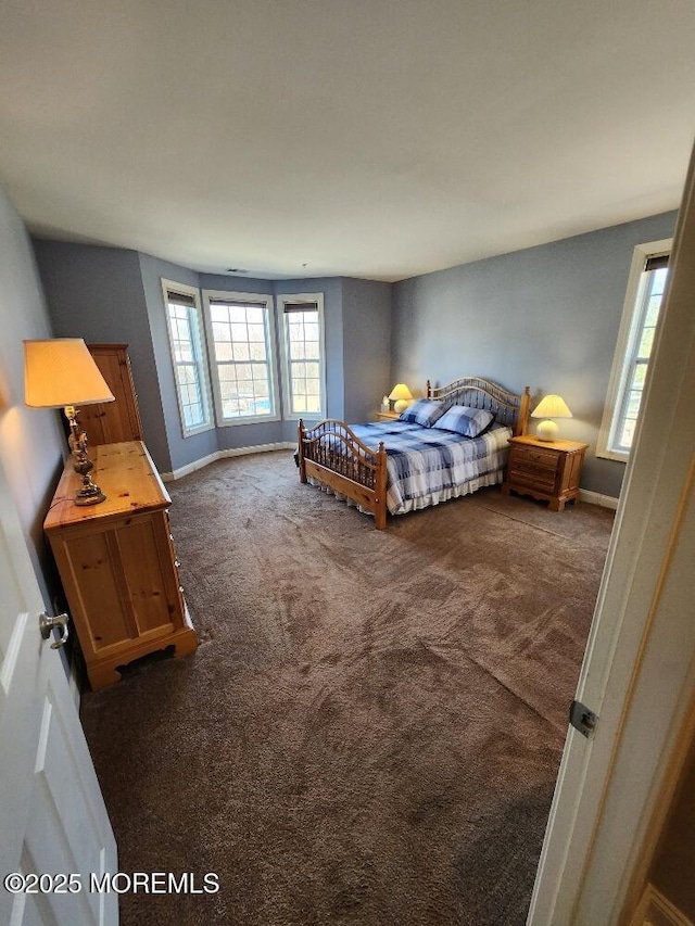 bedroom with dark carpet and baseboards