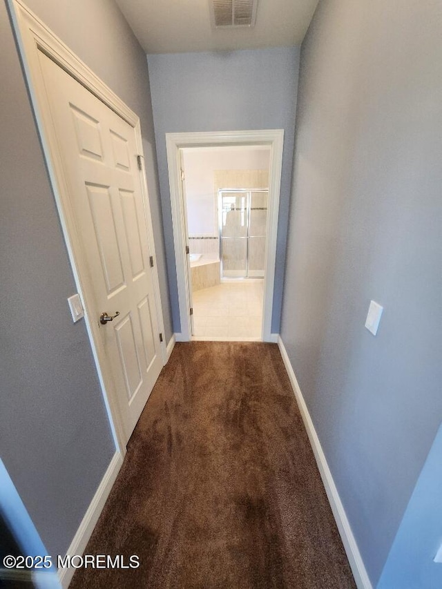 hall with visible vents, baseboards, and carpet