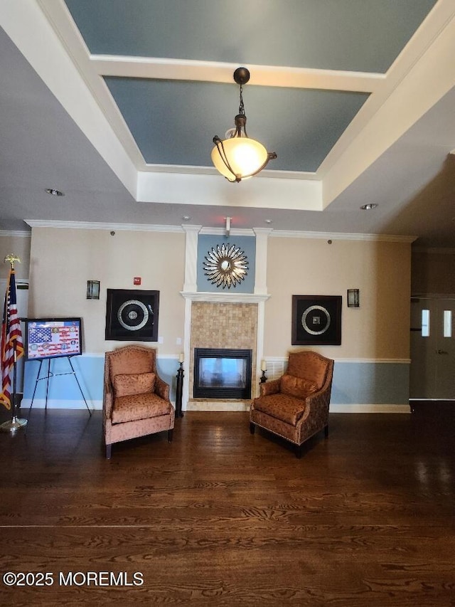 living area with a tray ceiling, wood finished floors, a fireplace, and ornamental molding