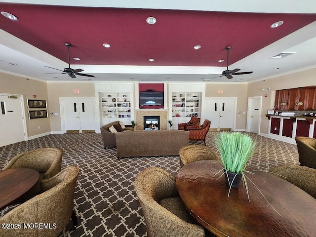 living area featuring dark colored carpet, a raised ceiling, and a ceiling fan