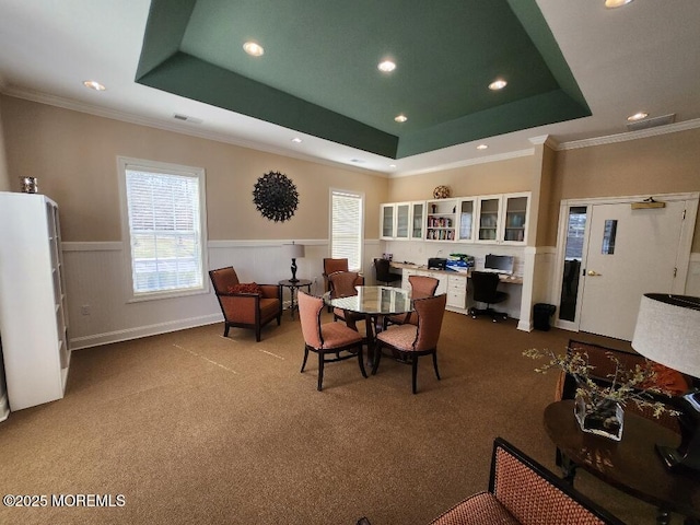 dining room with a tray ceiling, carpet floors, a wainscoted wall, and ornamental molding