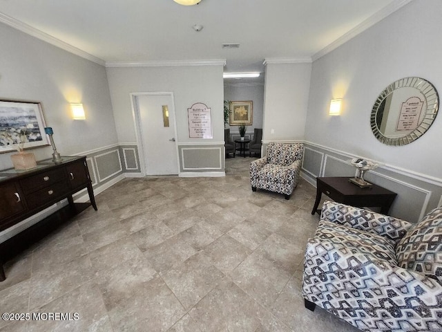 sitting room with a decorative wall, wainscoting, visible vents, and ornamental molding