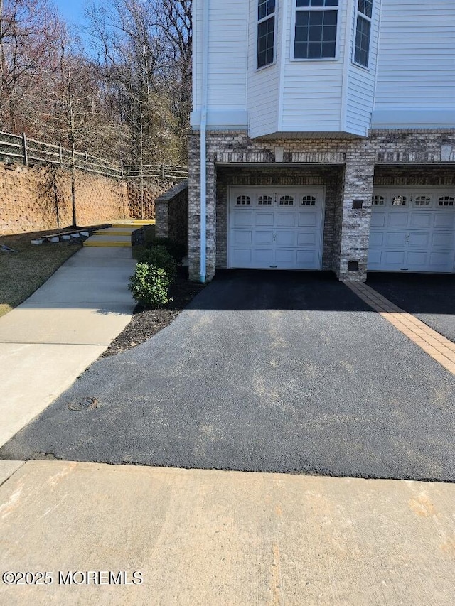 garage with aphalt driveway and fence