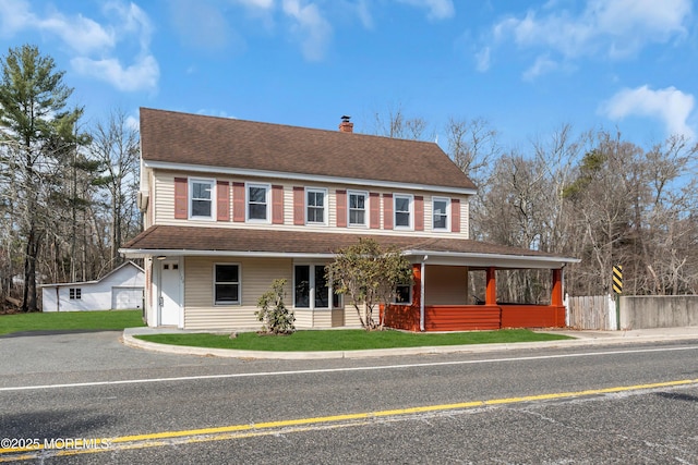 view of front of home with a front yard, an outbuilding, fence, roof with shingles, and a chimney