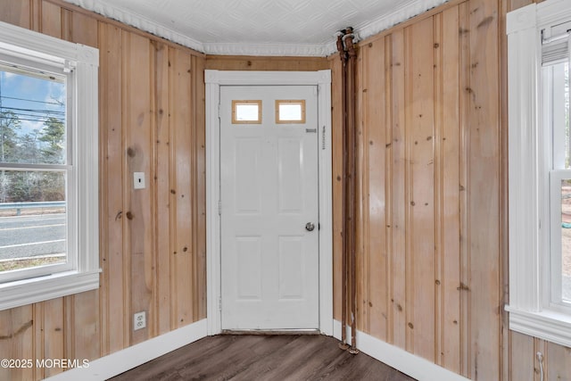 entryway featuring an ornate ceiling, baseboards, dark wood-style flooring, and wood walls