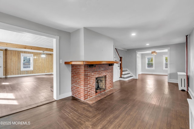 unfurnished living room featuring a wealth of natural light, stairs, and dark wood-type flooring