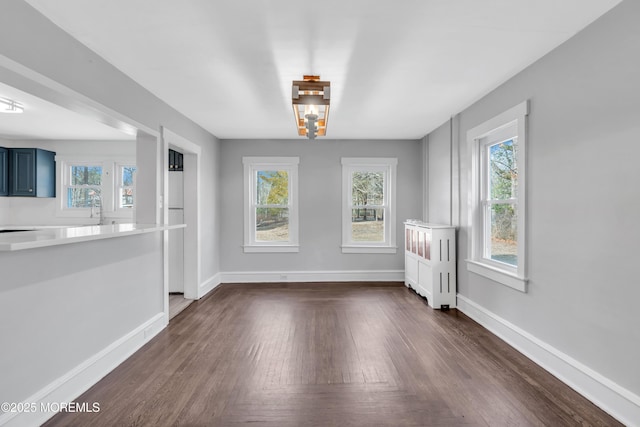 unfurnished dining area featuring baseboards and dark wood-style flooring