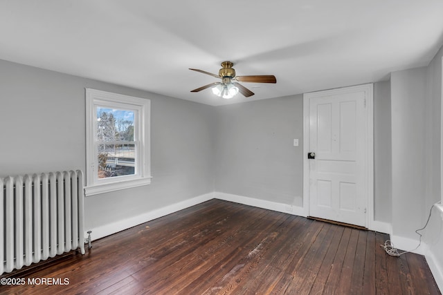 empty room featuring dark wood-style floors, a ceiling fan, radiator heating unit, and baseboards