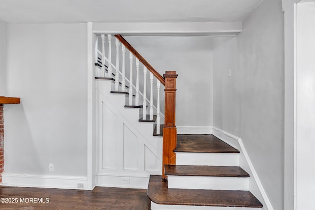 staircase featuring wood finished floors and baseboards