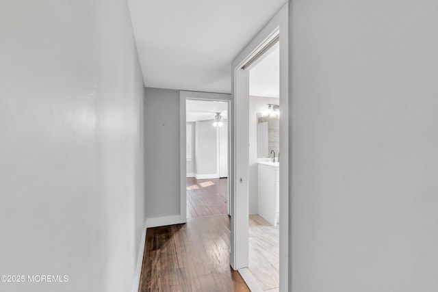 hall with a sink, baseboards, and hardwood / wood-style flooring