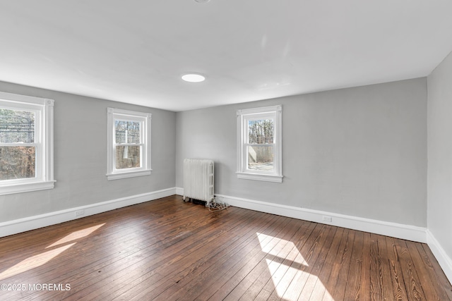 empty room featuring radiator, baseboards, and hardwood / wood-style flooring