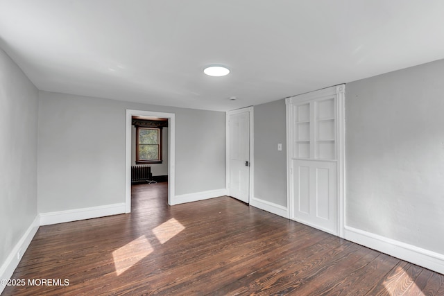 spare room featuring radiator heating unit, wood finished floors, and baseboards