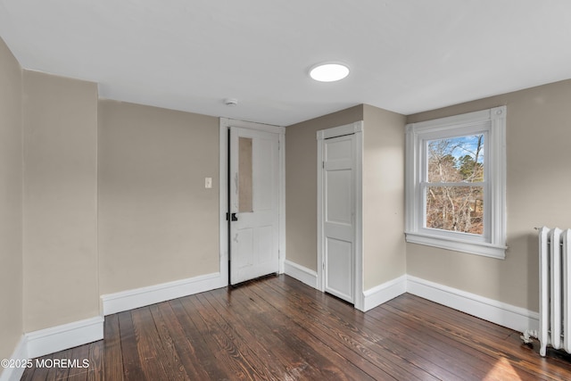 unfurnished room featuring dark wood finished floors, radiator, and baseboards