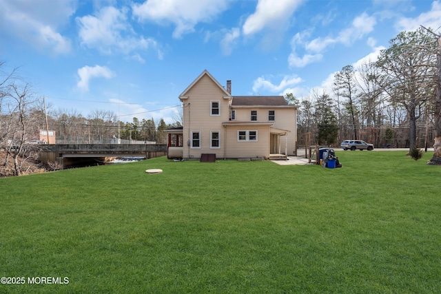 rear view of house with a lawn and a chimney