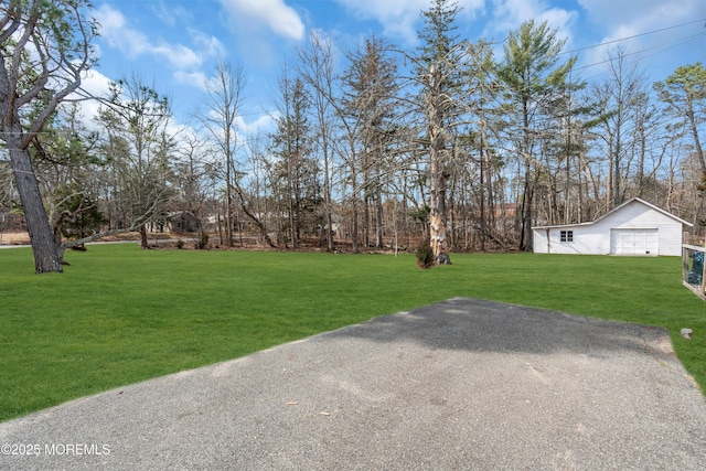 view of yard featuring an outbuilding, a garage, and aphalt driveway