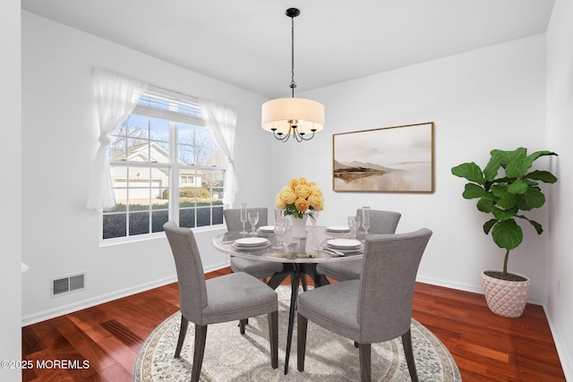 dining space with visible vents, baseboards, an inviting chandelier, and wood finished floors