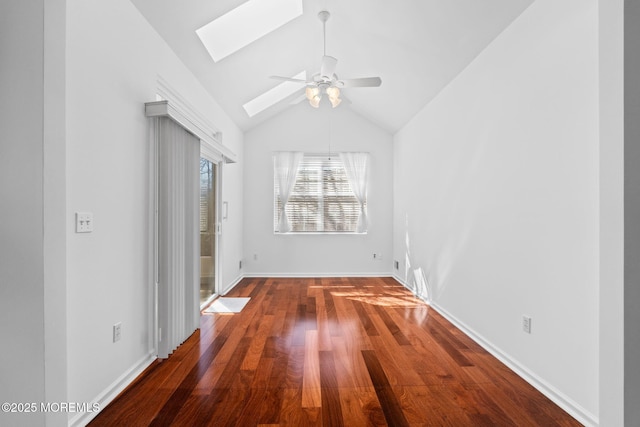 spare room with wood finished floors, a ceiling fan, baseboards, and lofted ceiling with skylight