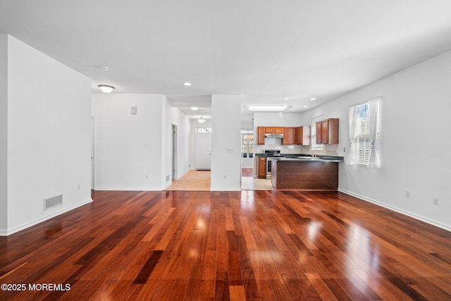 unfurnished living room with visible vents, baseboards, hardwood / wood-style floors, recessed lighting, and a sink