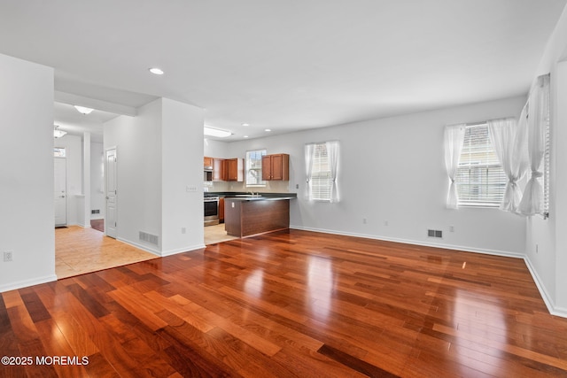 unfurnished living room featuring hardwood / wood-style flooring, baseboards, and visible vents