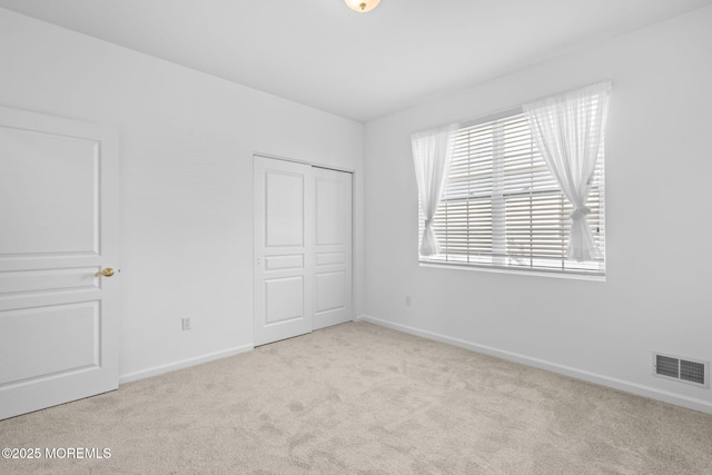 unfurnished bedroom featuring visible vents, baseboards, a closet, and carpet flooring