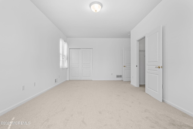 unfurnished bedroom featuring visible vents, light carpet, and baseboards