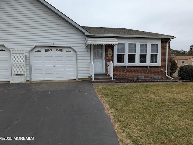 view of front facade featuring roof with shingles, a front lawn, a garage, aphalt driveway, and brick siding