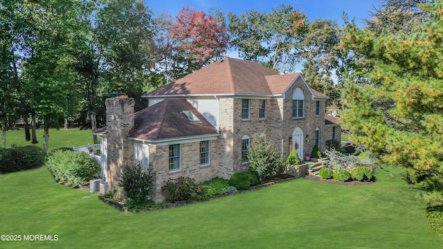 colonial-style house featuring brick siding, central AC unit, and a front yard