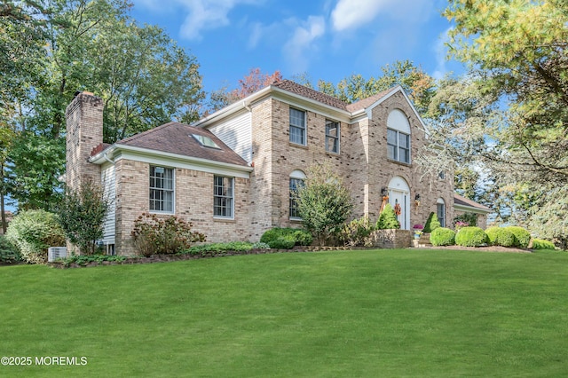 view of front of property with a front lawn, brick siding, and a chimney