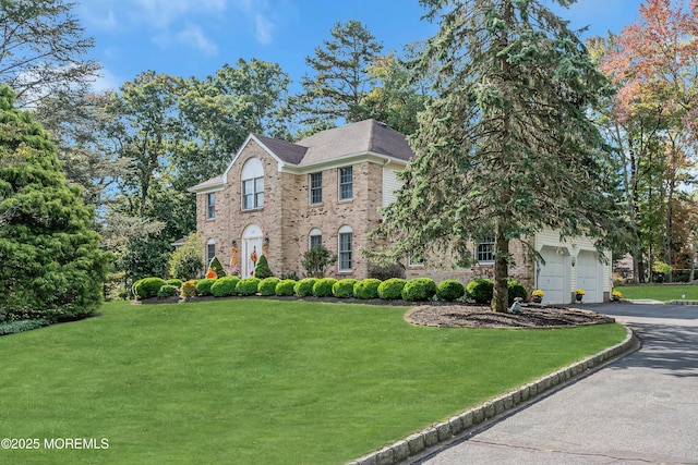 view of front facade with brick siding, driveway, and a front yard