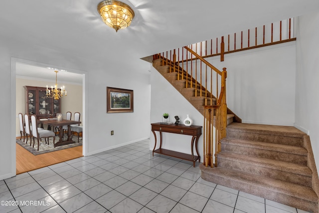 stairs with tile patterned floors, baseboards, an inviting chandelier, and ornamental molding